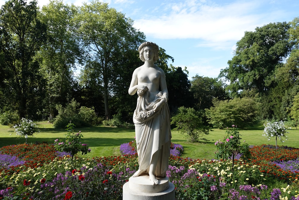 a statue of a woman in a flower garden