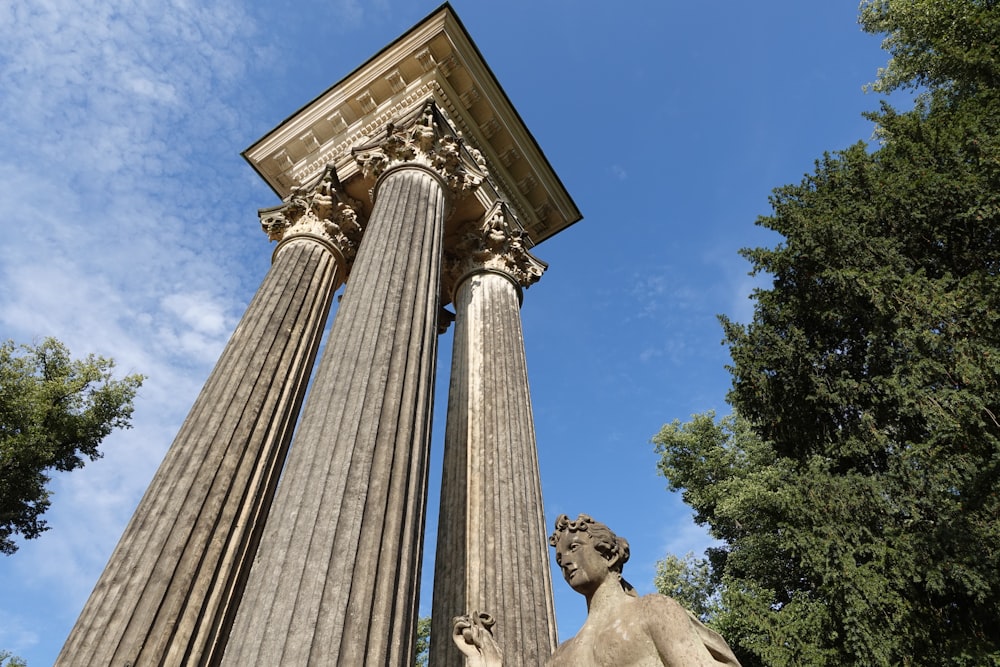 una statua di un uomo in piedi accanto a un alto pilastro