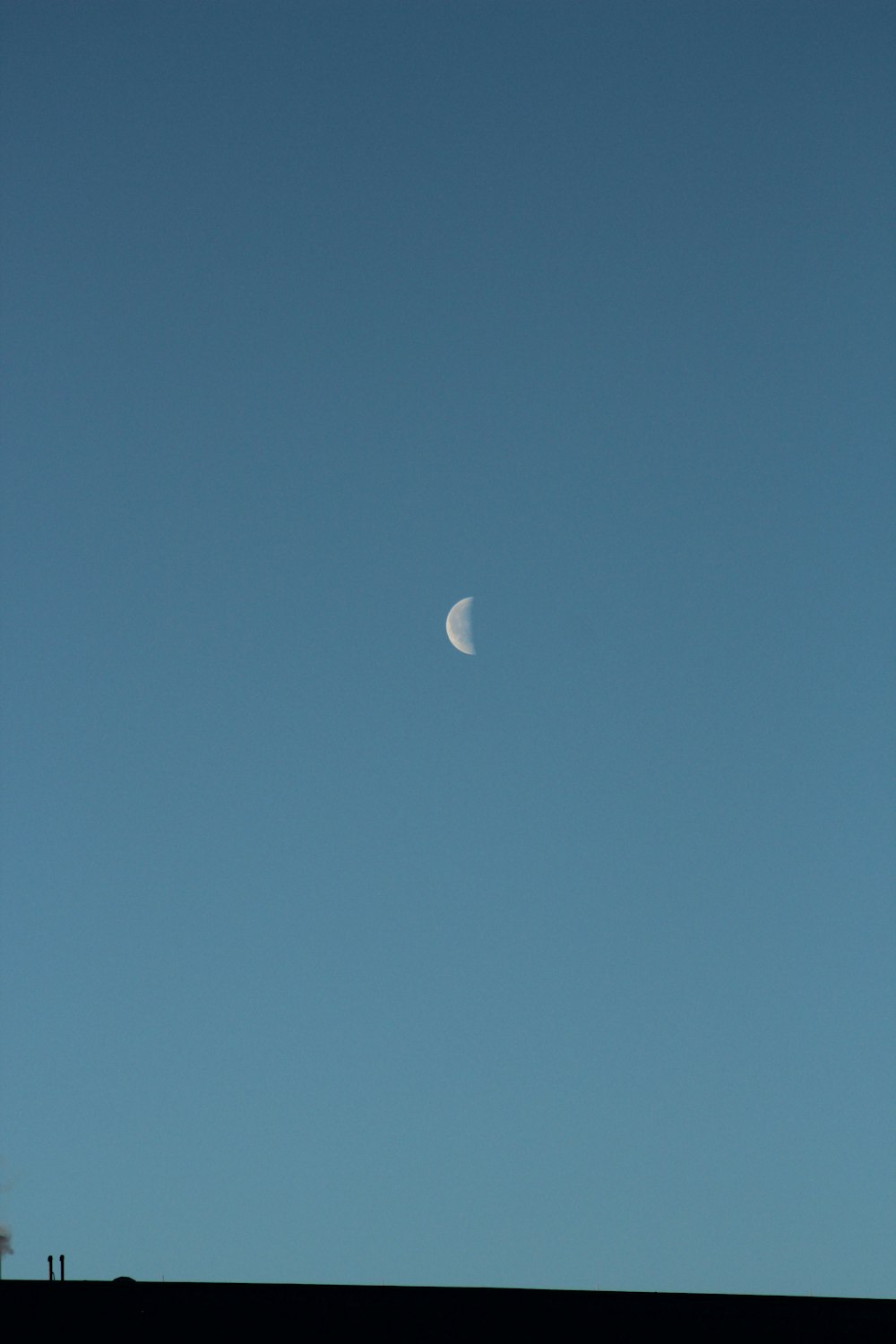 a half moon is seen in a clear blue sky