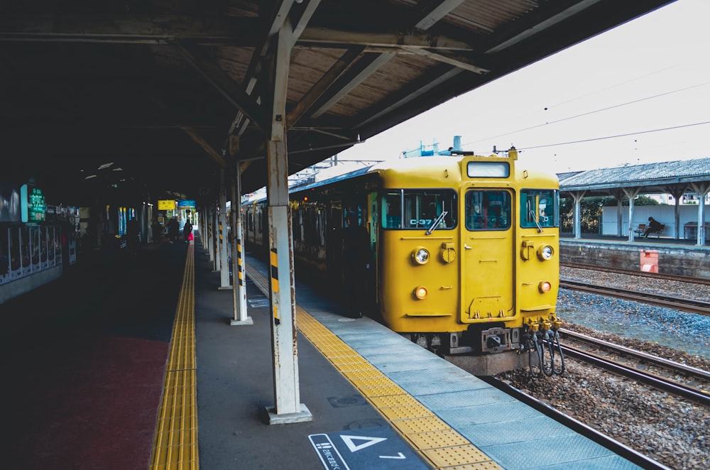 Ein gelber Zug fährt in einen Bahnhof ein