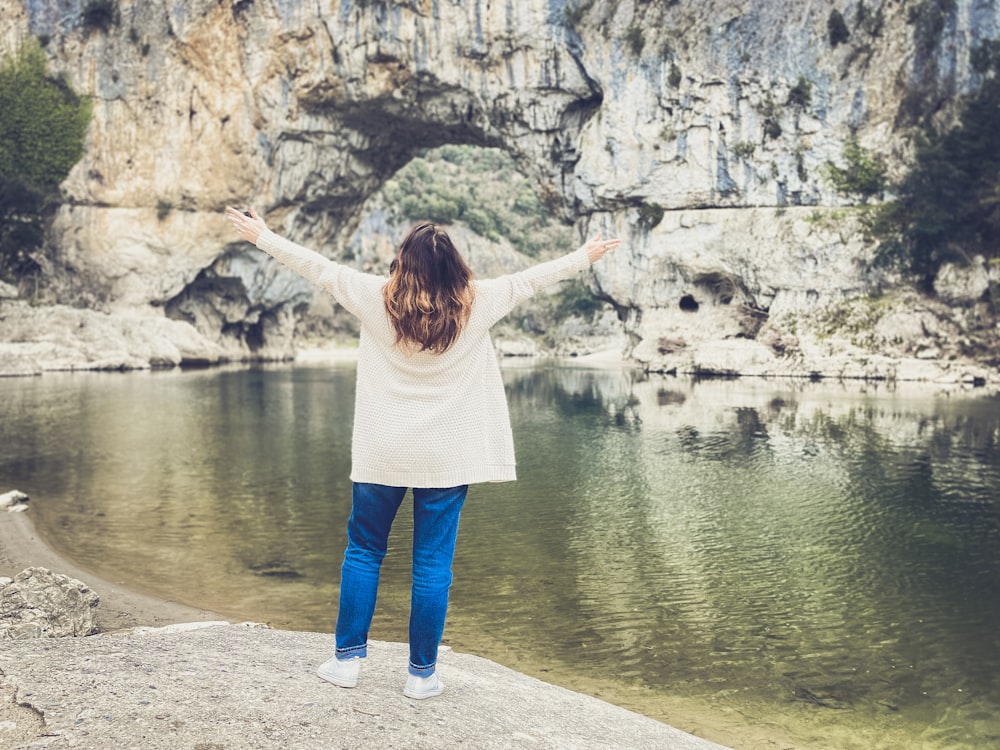 Una donna in piedi su una roccia vicino a uno specchio d'acqua