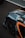 A close-up of a sports car's rear section with aerodynamic features. The car is adorned with racing decals and has a sleek, modern design. The tire's branding is visible, and a QR code is present on the car's body.