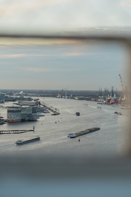 Aerial view of multiple barges lined up along an inland waterway in a small town.