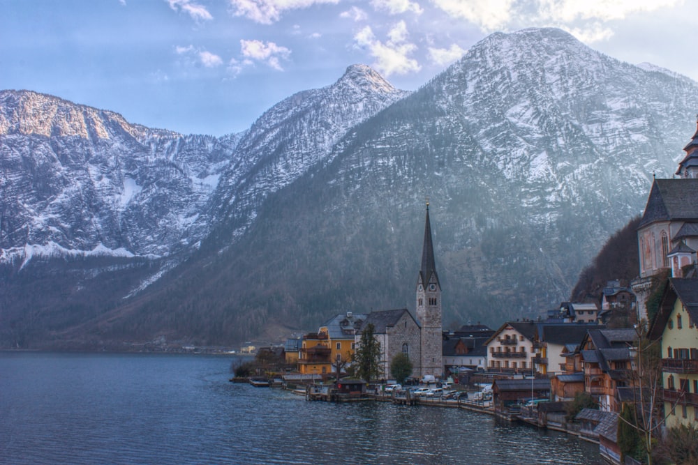 a town on the shore of a lake with mountains in the background