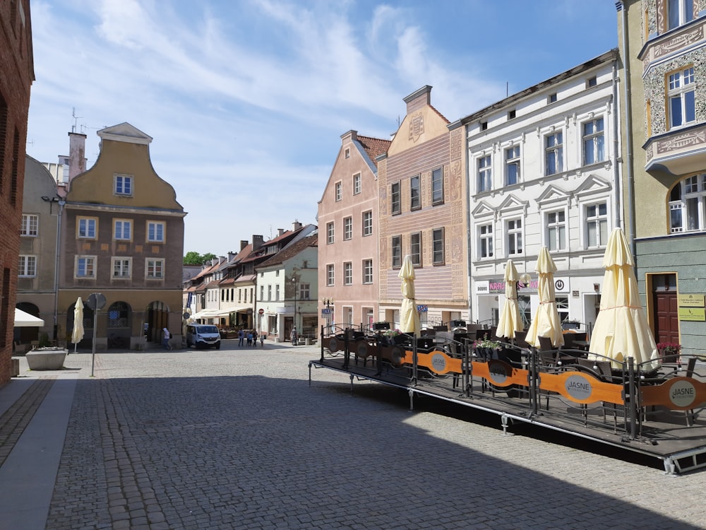 a cobblestone street lined with buildings and umbrellas