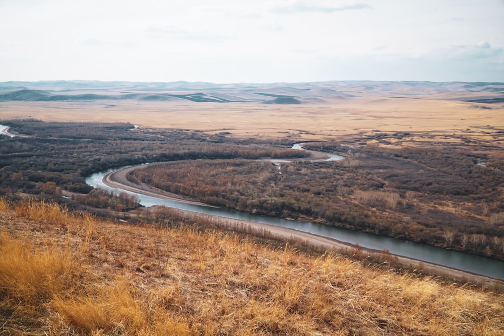 a river running through a dry grass covered field