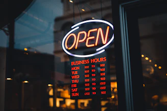 a neon sign that says open in front of a window