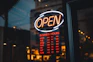 a neon sign that says open in front of a window