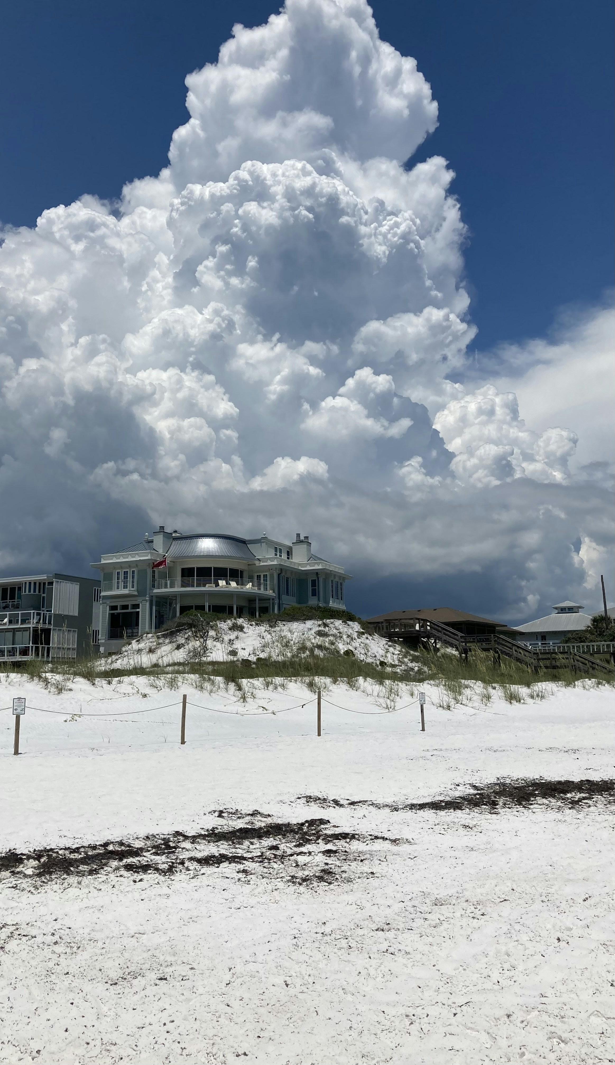 A large cloud looms over a building on a beach photo – Free Cloud Image ...