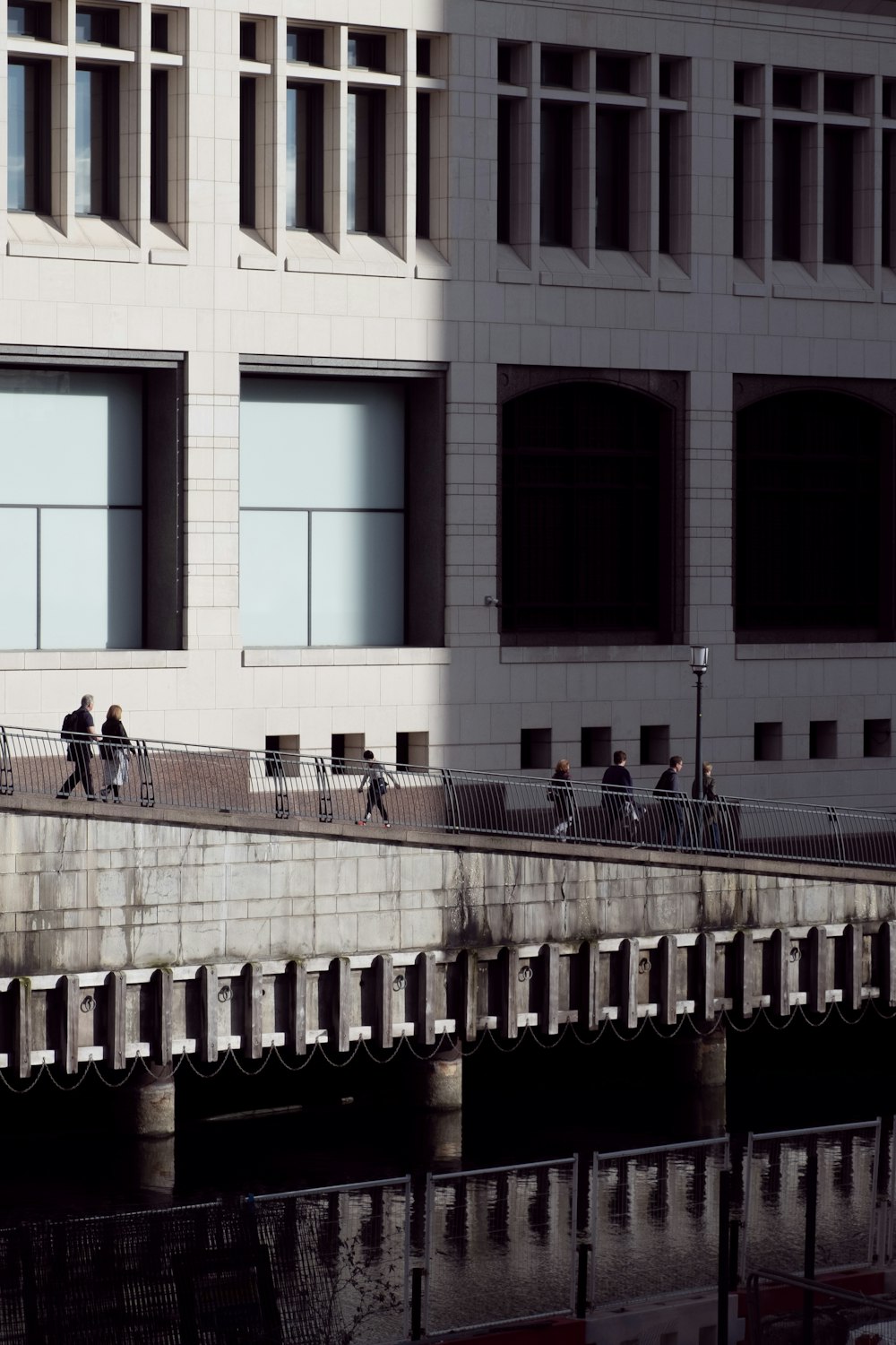 a group of people walking across a bridge over water