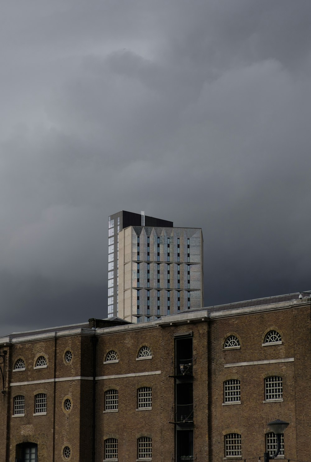 a tall building sitting next to a tall building under a cloudy sky