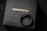 A black ring with a detailed snake design rests on a dark textured surface, with the brand name COPPERTIST.WU displayed in gold lettering.