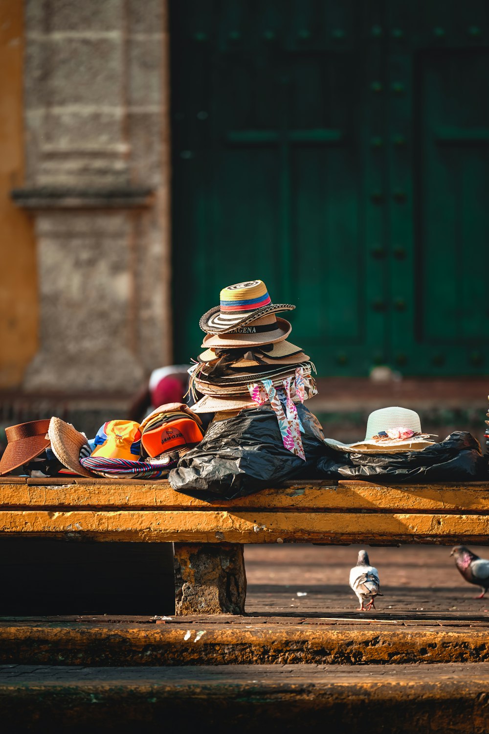 a pile of hats sitting on top of a wooden bench