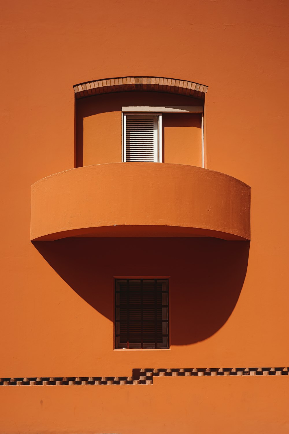 an orange building with a round window and balconies