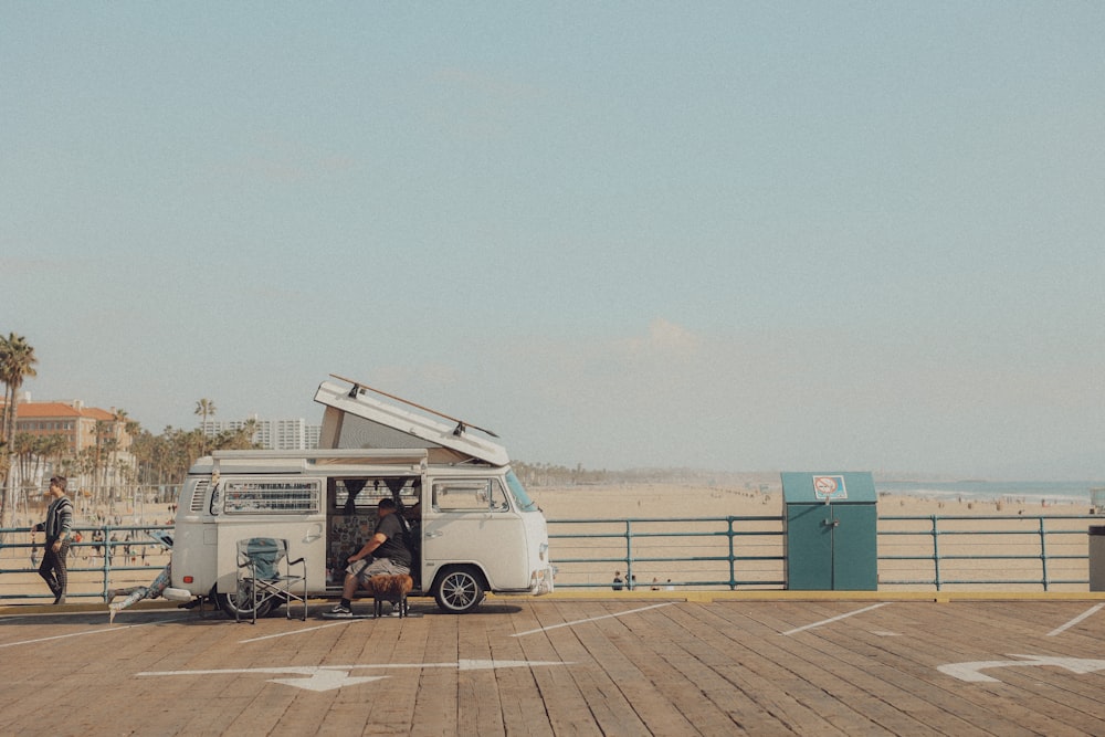 a white van parked on top of a pier next to the ocean