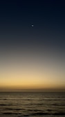 A close-up of a glowing crescent moon over a calm sea.
