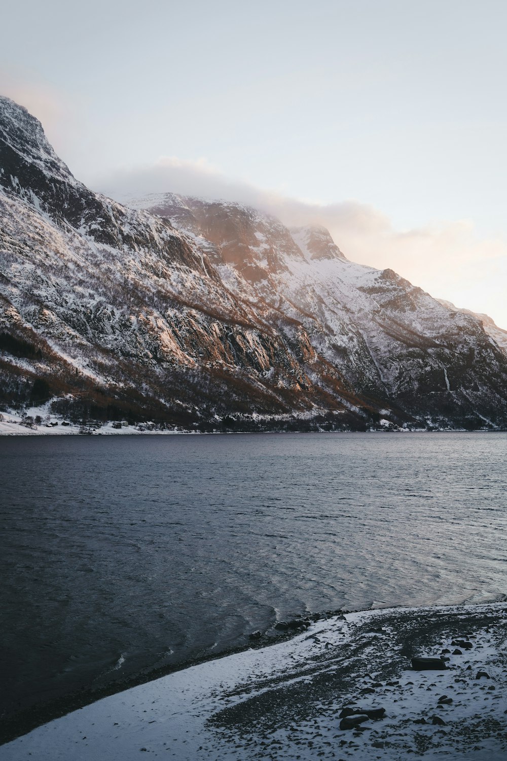 a mountain covered in snow next to a body of water