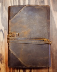 a brown leather journal sitting on top of a wooden table