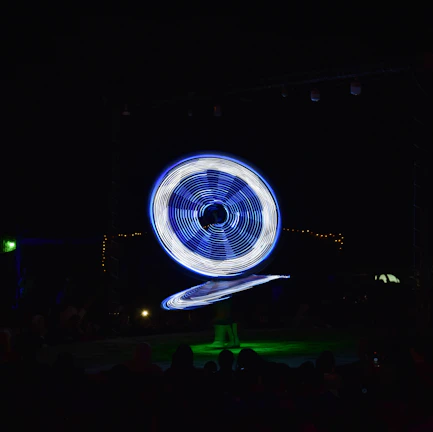 A dazzling spinning baton creating vibrant light patterns at an outdoor night event.