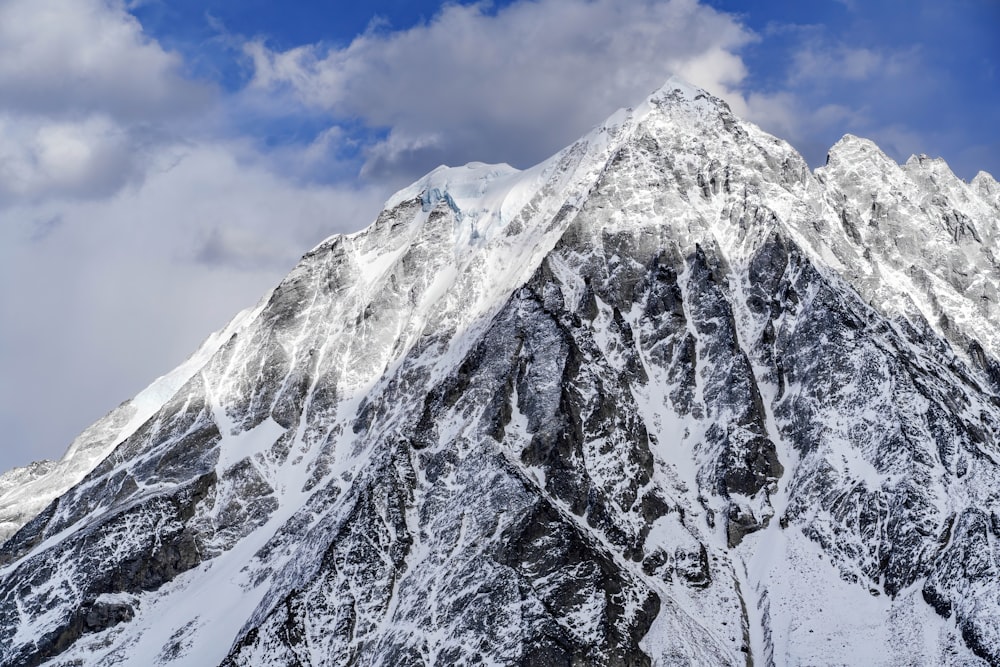 a large mountain covered in snow under a cloudy sky