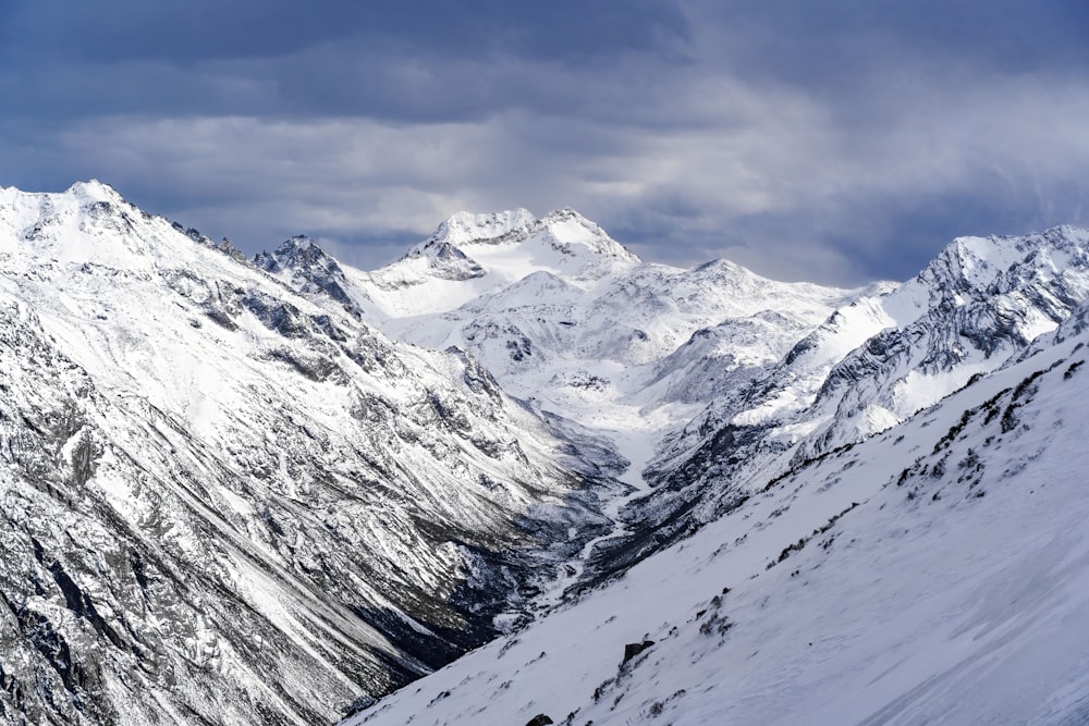 a snow covered mountain range under a cloudy sky