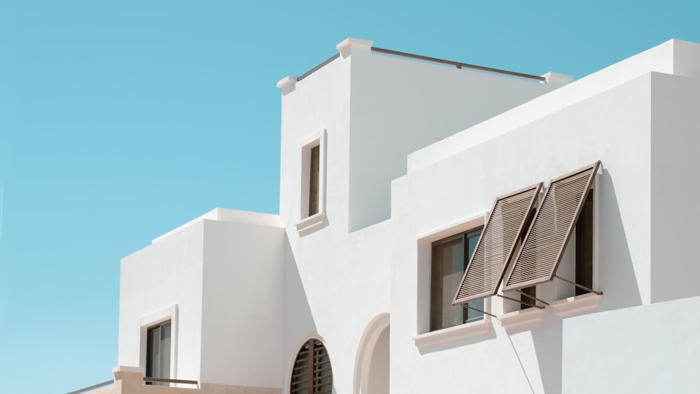 a white building with two windows and shutters