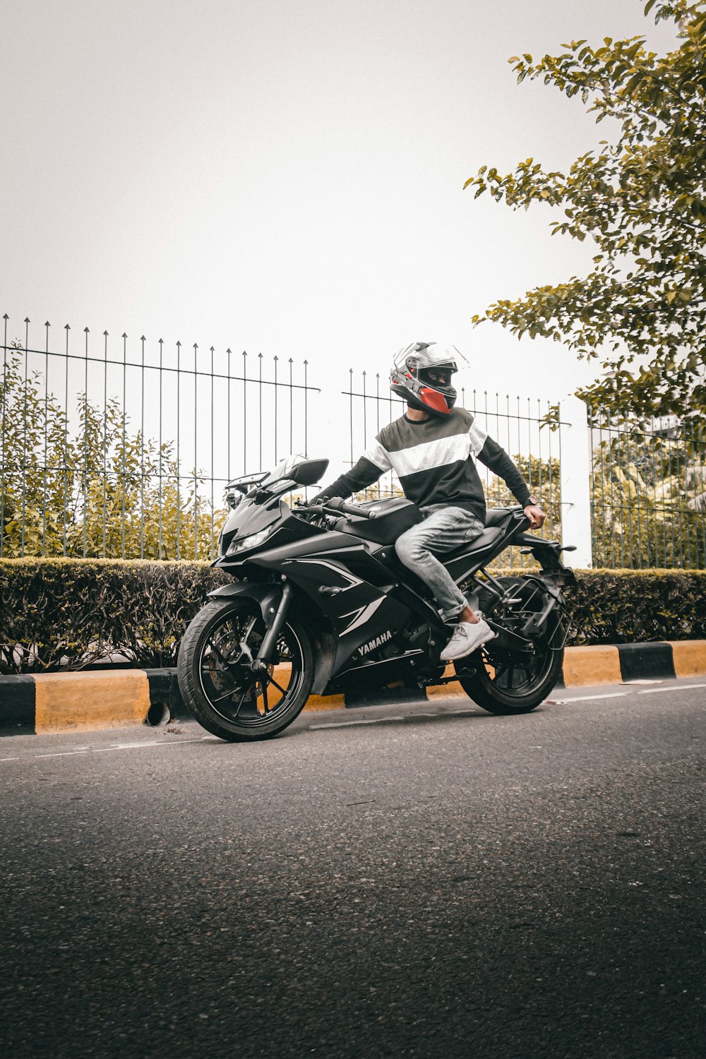 a man riding a motorcycle down a street next to a fence