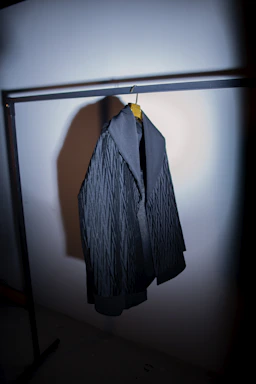 A sleek, modern streetwear jacket hanging on a minimalist rack with soft lighting.