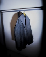 Close-up of a high-quality wool coat hanging on a minimalist rack.