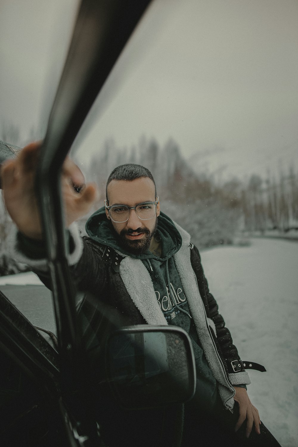 a man with a beard and glasses sitting in a car