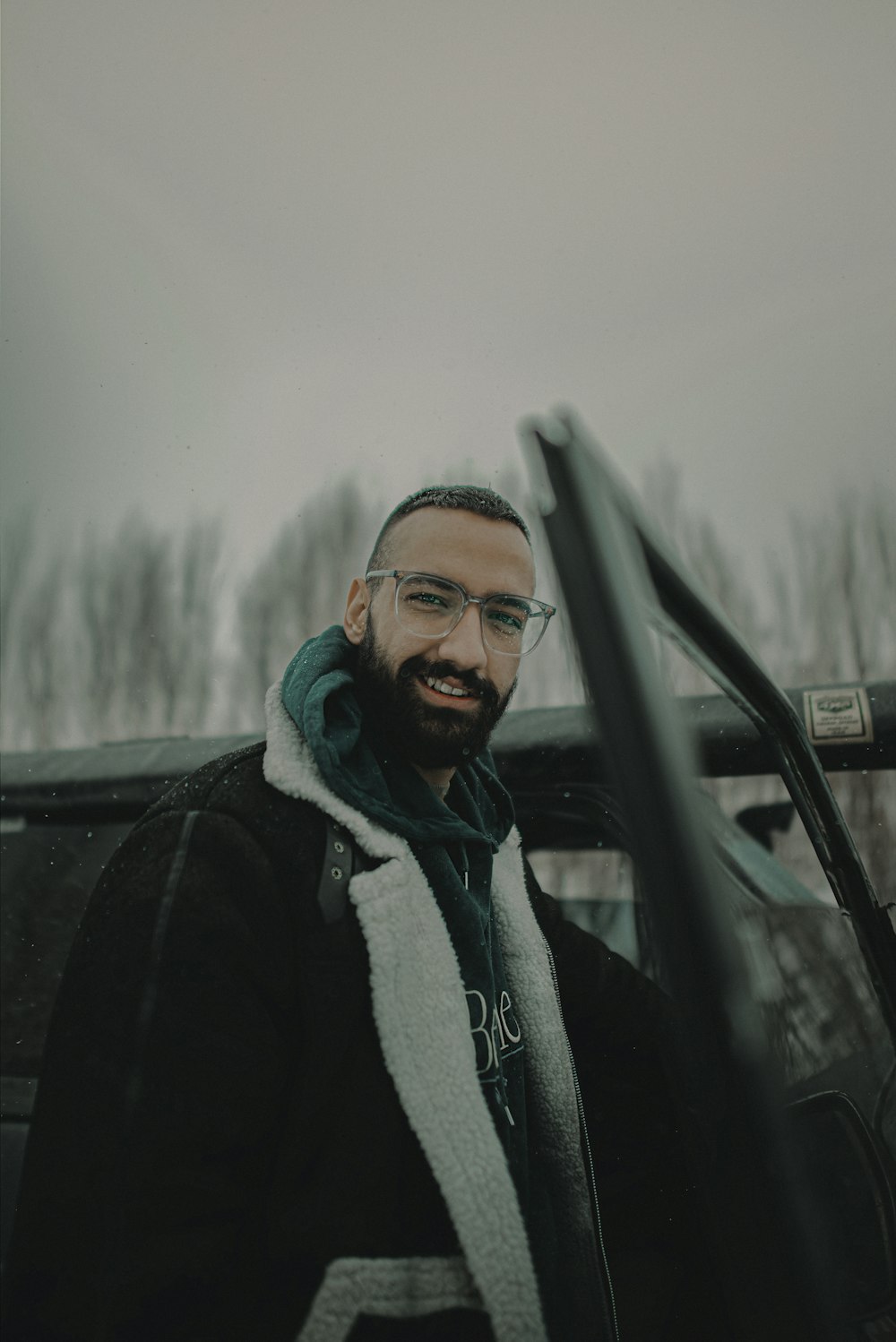 a man with a beard and glasses standing in front of a truck