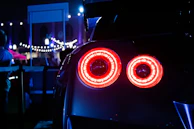 Rear view of a sporty car speeding on a dark road with red neon lights
