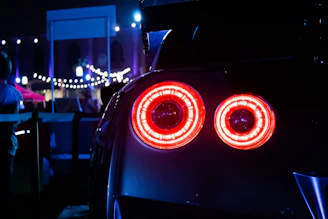 Rear view of a sporty car speeding on a dark road with red neon lights