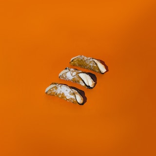 Artisan hand delicately piping cannoli filling inside the vintage triporteur under warm natural light.