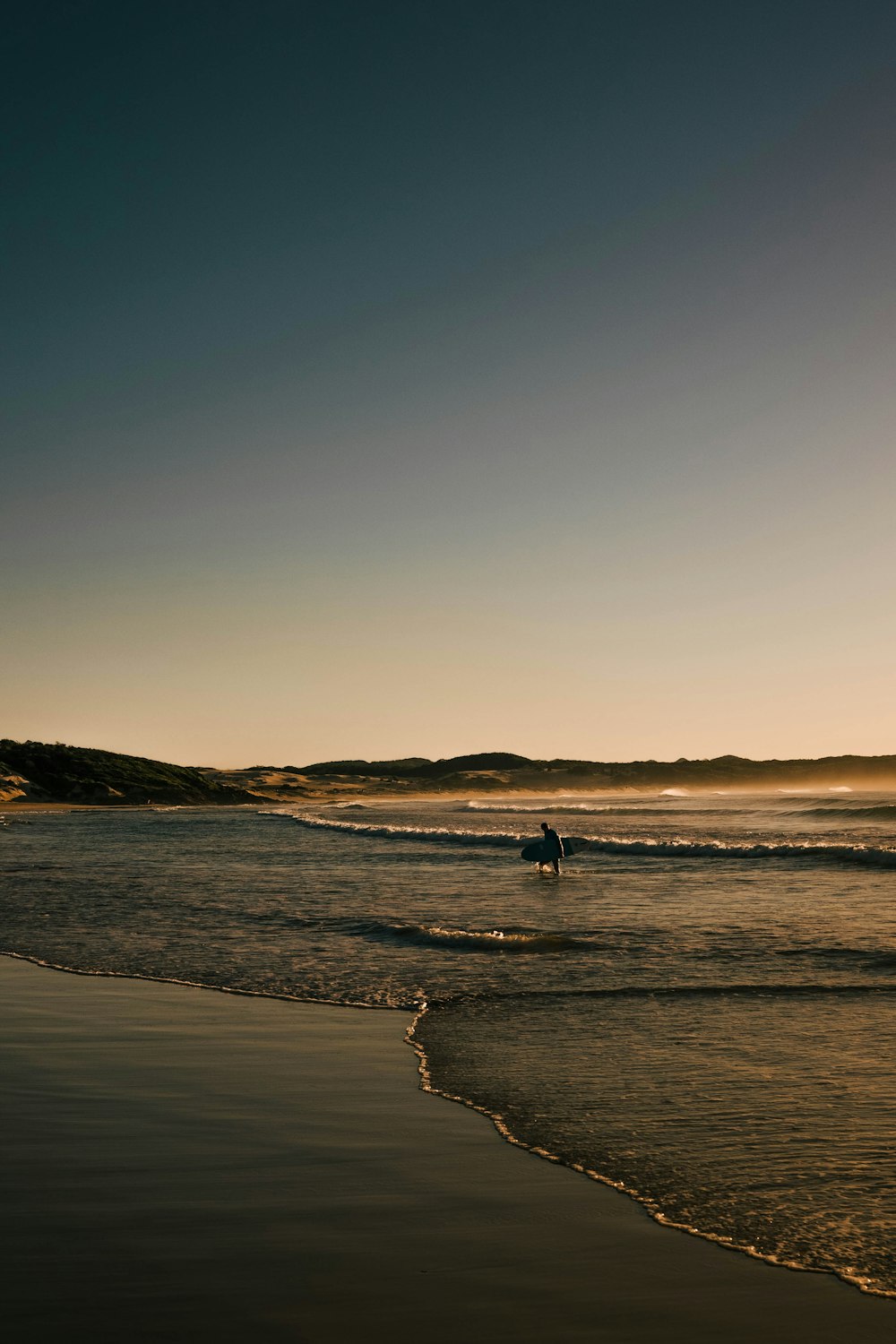 a person walking on the beach with a surfboard