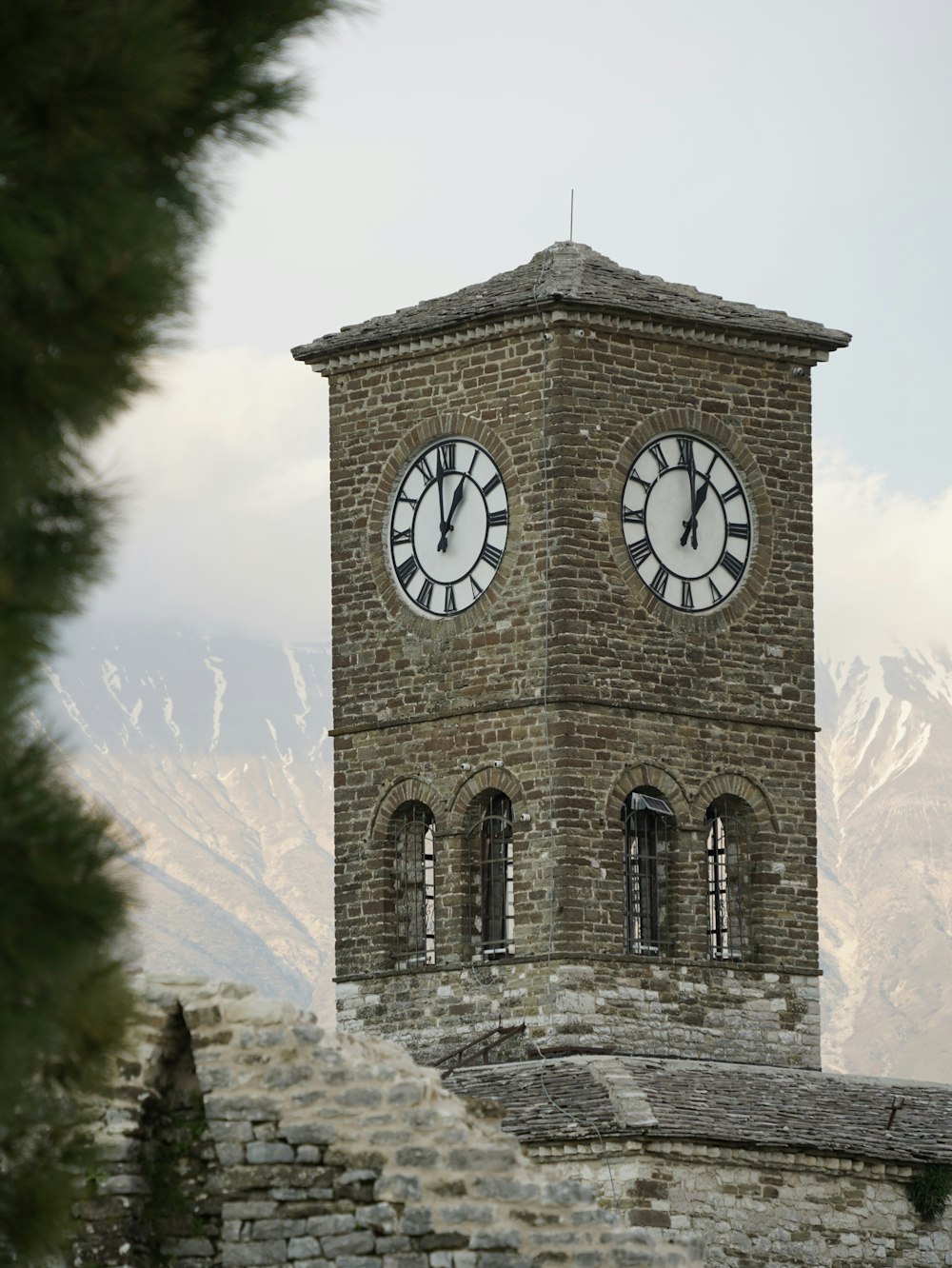 a large brick clock tower with two clocks on each of it's sides