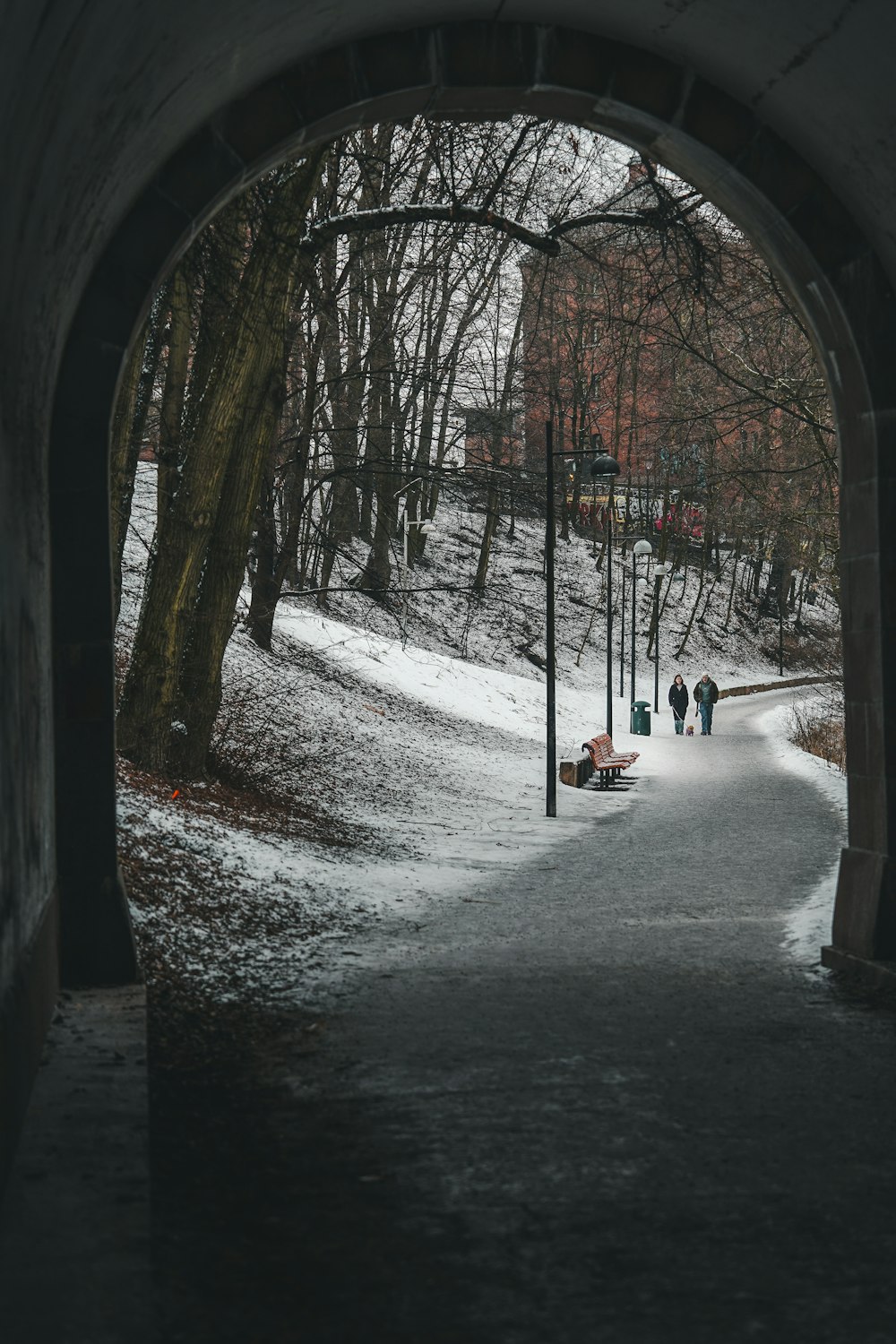 people walking down a snowy path under a tunnel