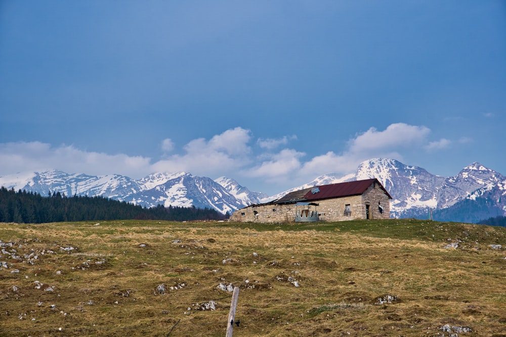a small house on a grassy hill with mountains in the background
