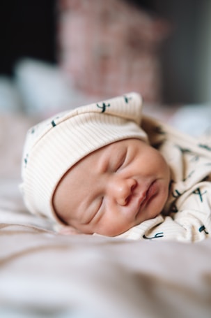 a baby is sleeping on a bed wearing a hat