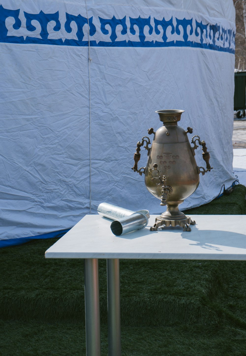 um vaso de prata sentado em cima de uma mesa branca