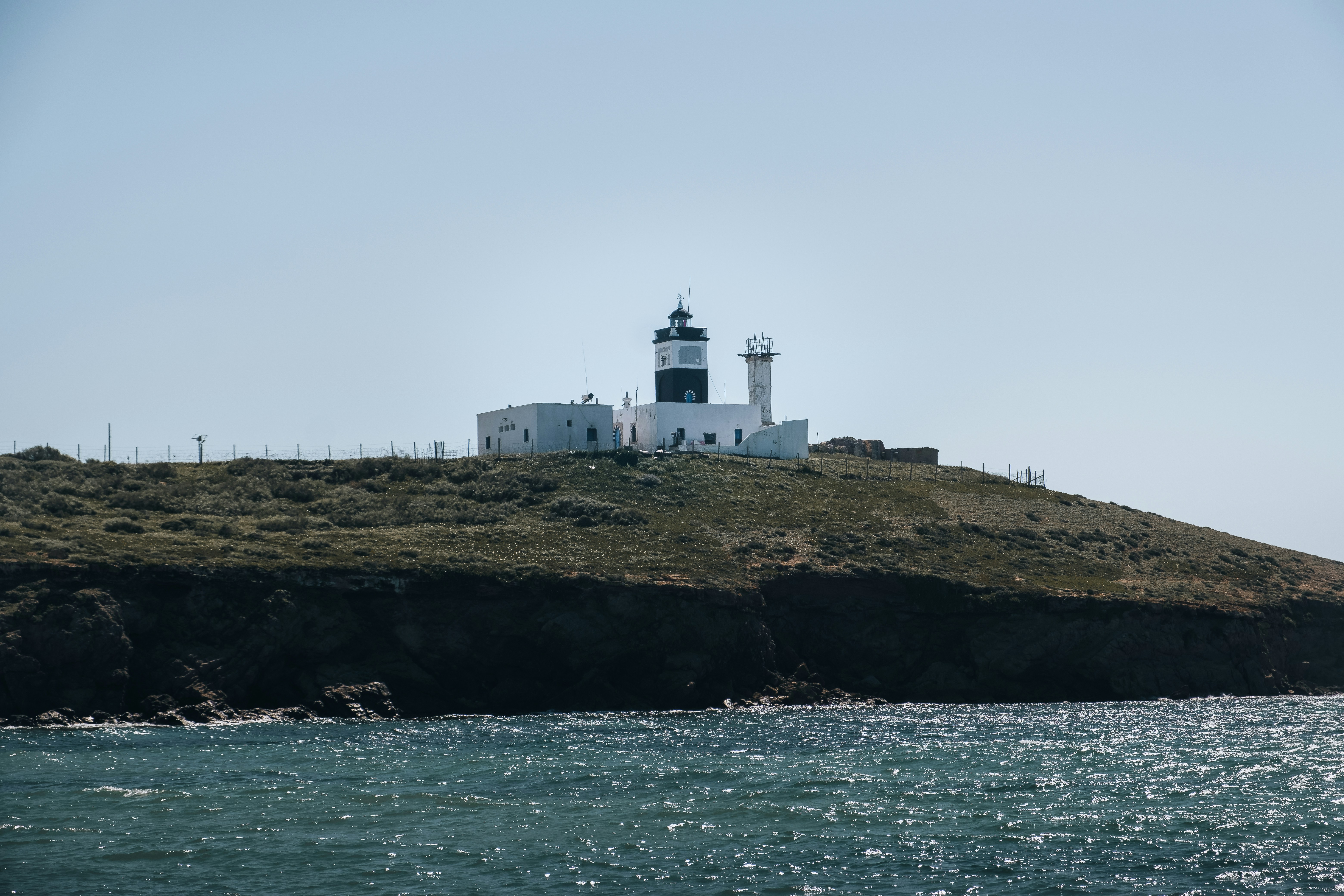 a lighthouse on a hill overlooking a body of water