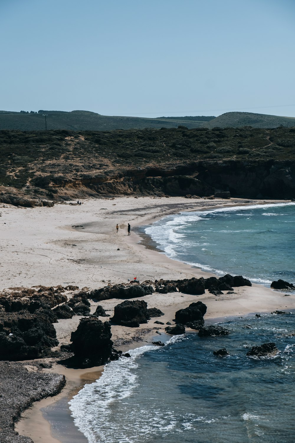 a sandy beach next to a body of water