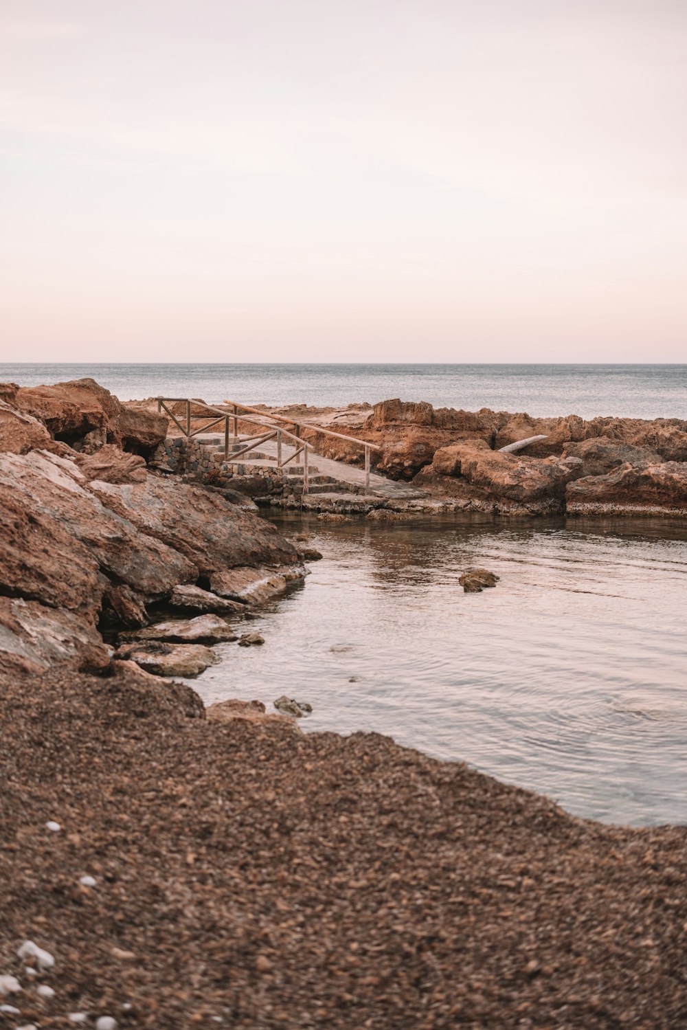 a rocky shore with a wooden walkway leading to the water