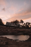Sunset over a modern apartment complex near the beach with palm trees swaying