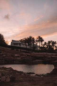 Sunset over a modern apartment complex near the beach with palm trees swaying