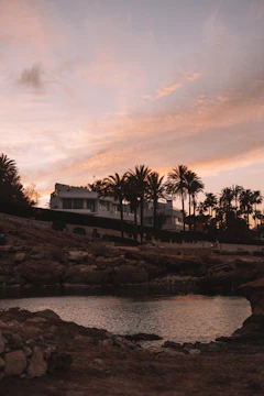 Sunset view of modern beachfront condos with palm trees swaying.