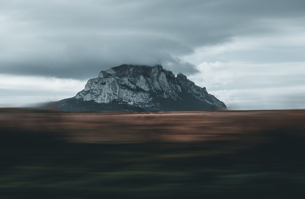 a mountain is seen in the distance under a cloudy sky