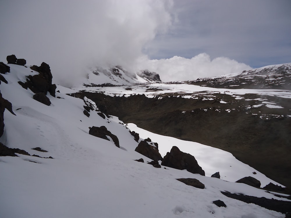 uma montanha coberta de neve com uma nuvem no céu