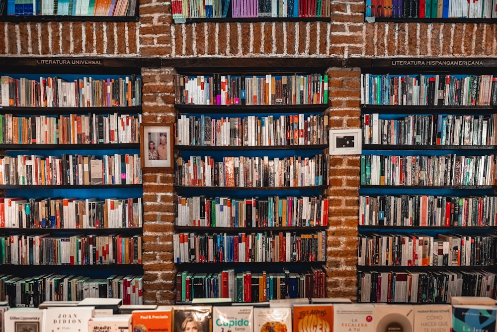 a bookshelf filled with lots of books next to a brick wall