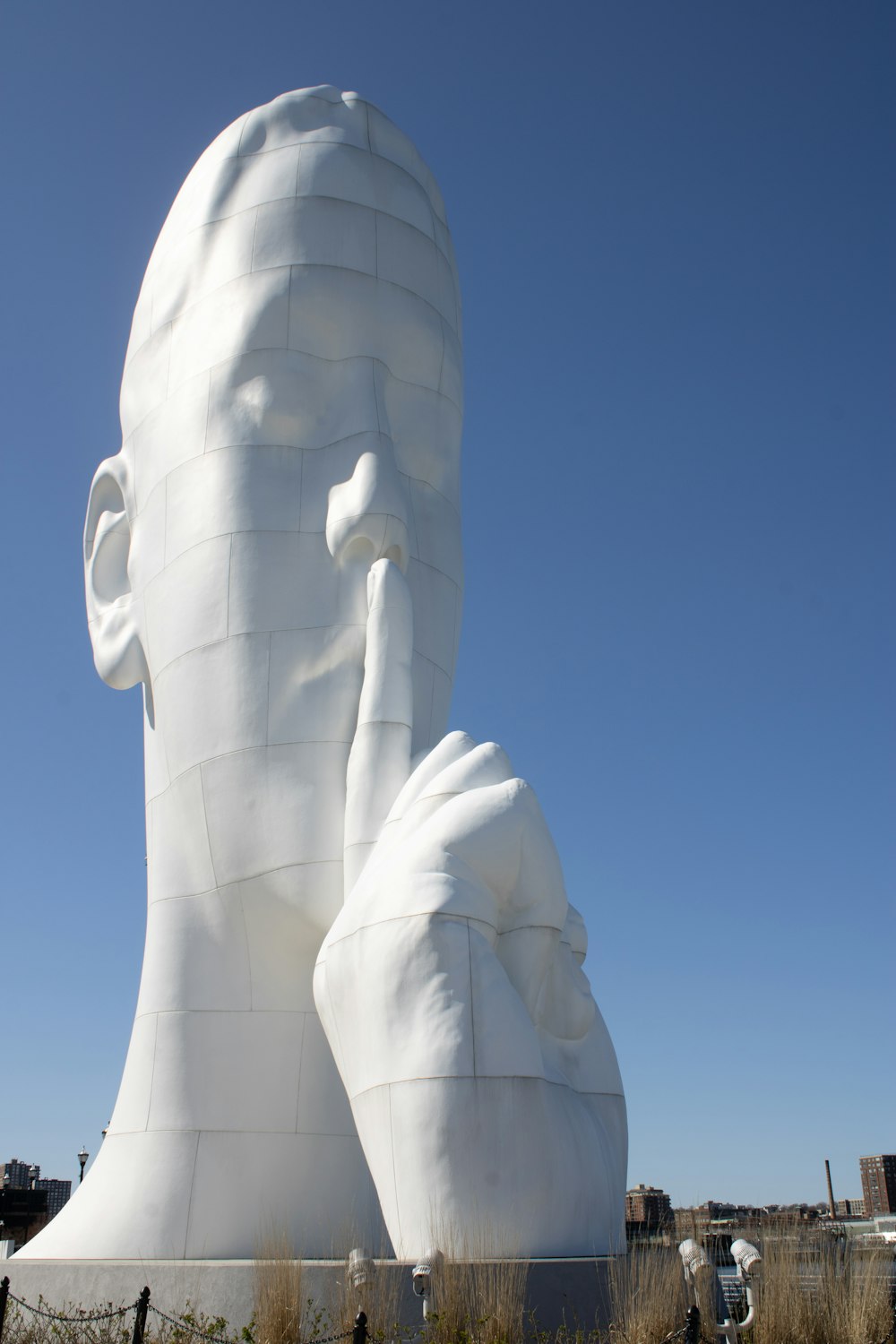 a large white sculpture of a man with his hands on his face